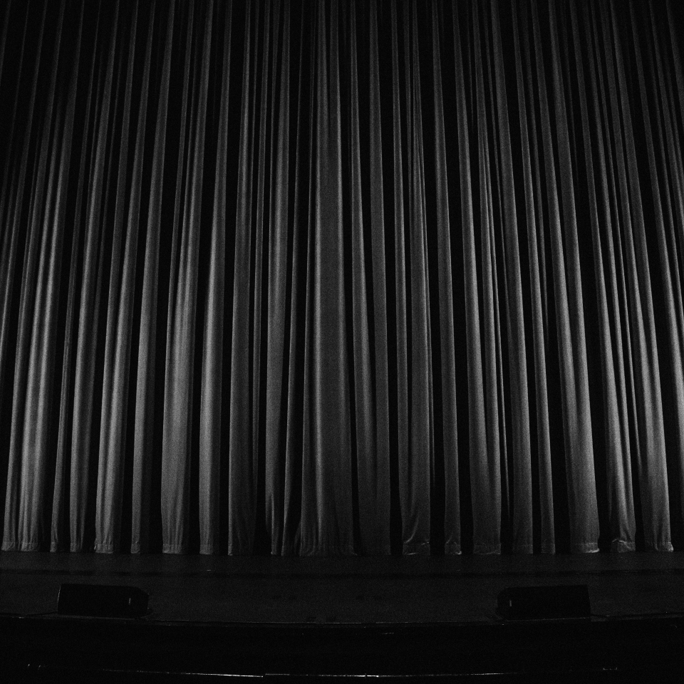Black and white photo of closed stage curtains.