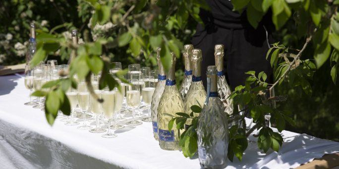 Champagne och champagneglas på ett vitdukat bord.