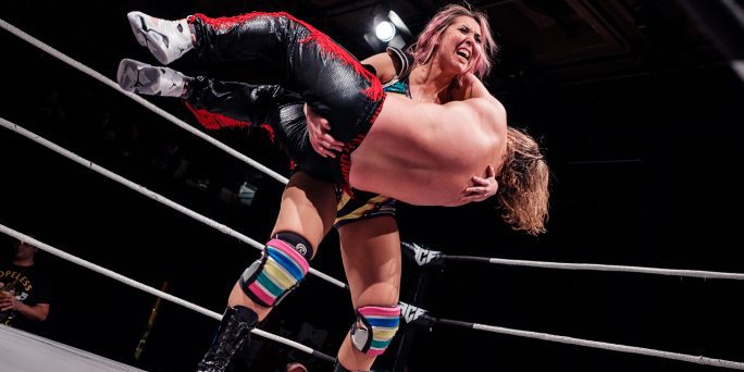 Reimi lyfter Sebastian Vauhkonen upp i luften i en fribrottningsring.