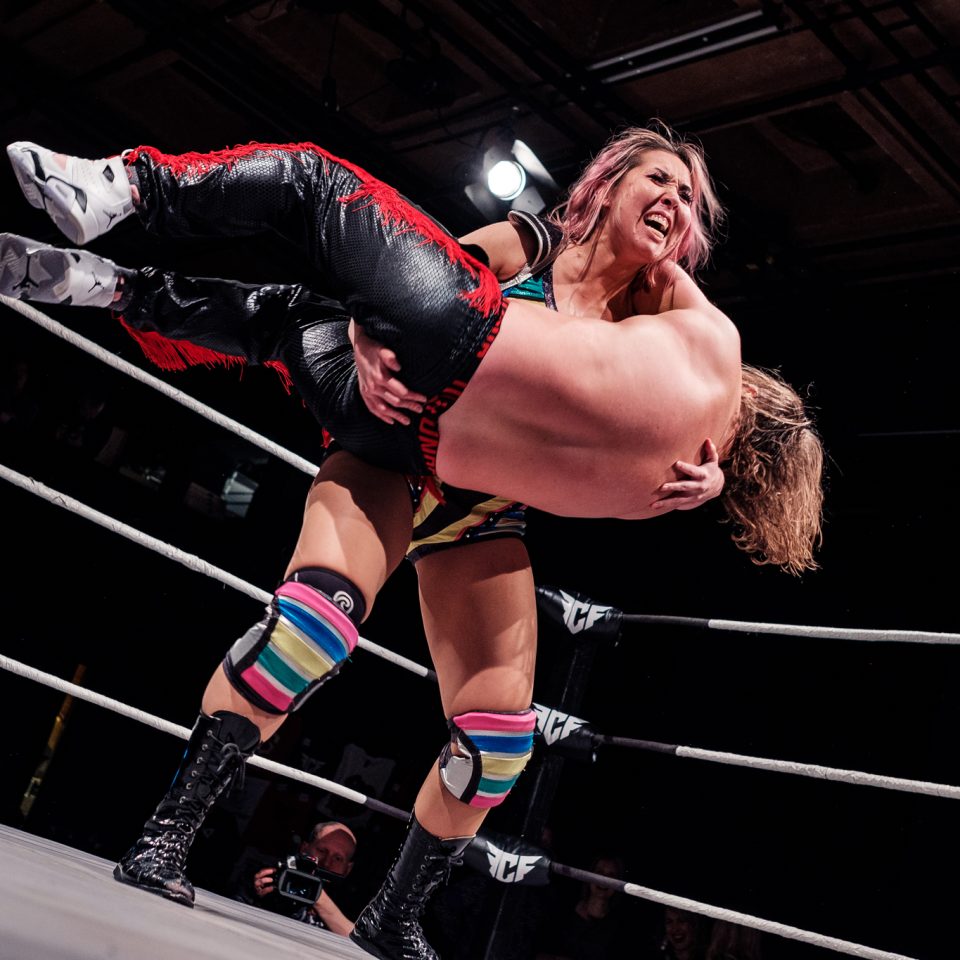 Reimi lyfter Sebastian Vauhkonen upp i luften i en fribrottningsring.