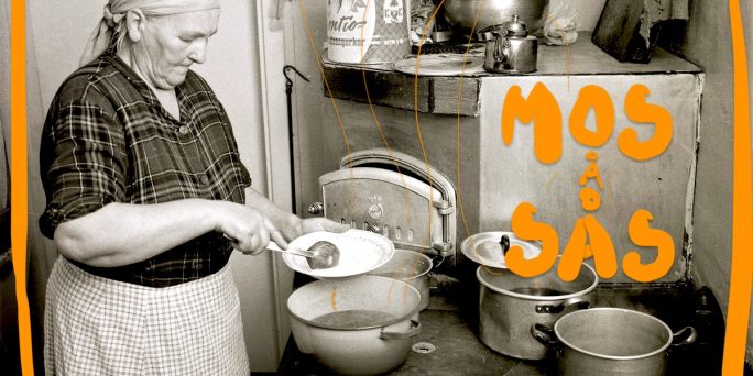 En äldre kvinna, klädd i gammaldags kläder, står framför spisen och sätter mat på en tallrik, svartvit bild.